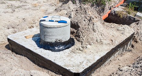 A septic tank riser is surrounded by concrete to make accessing the septic system easier.