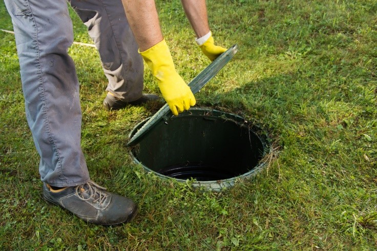 Homeowner opening septic tank before septic system maintenance pro's arrival