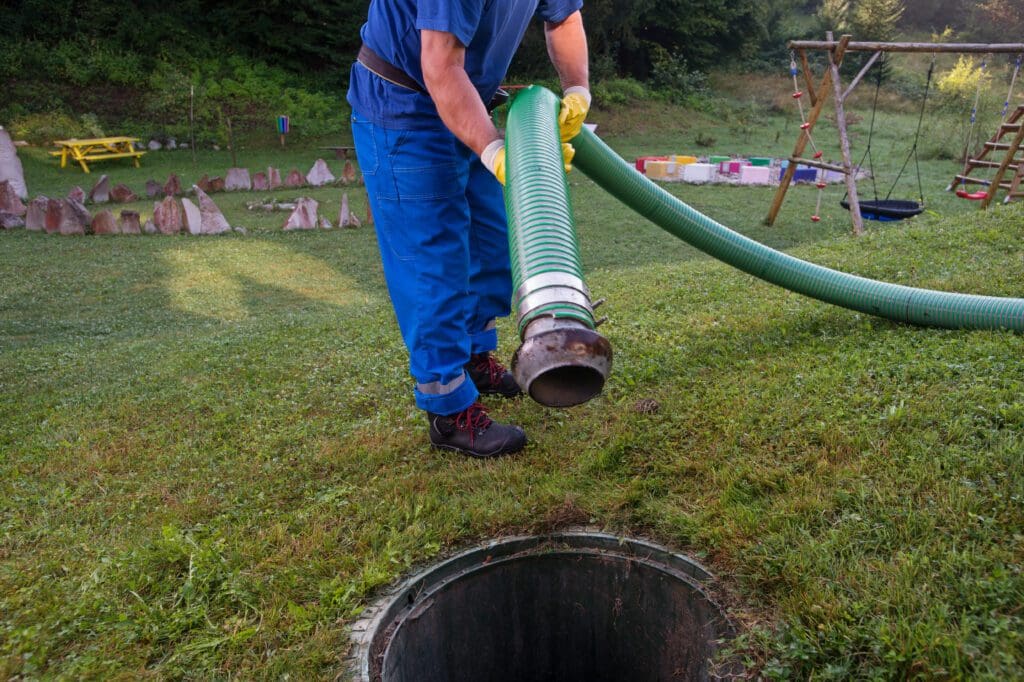A septic tank technician places a hose in a septic system to pump it out.